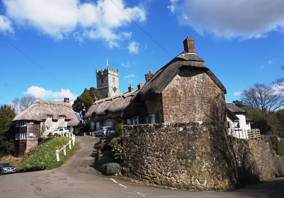 Thatched stone cottages below the church tower at Godshill on the Isle of Wight