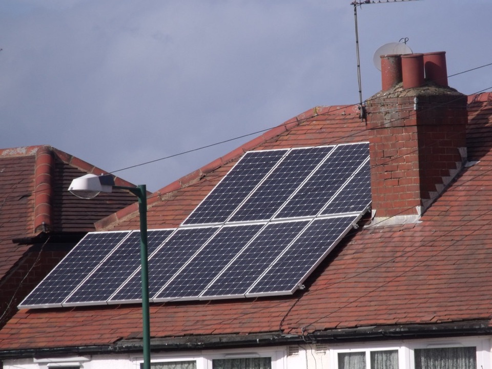 Solar panels fitted across the tiled pitch of a house roof in England